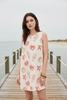 Front image of dress with coral colored shell, seahorse, starfish, and lobster print.