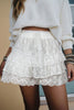 White lace skirt worn with a white sweater against a neutral background