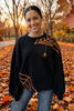 Black knit sweater with embroidered orange spider and web. 