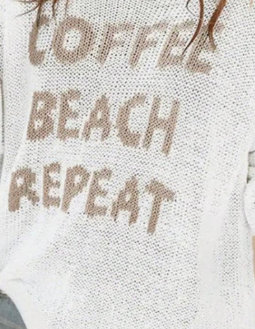 Close-up of a white knit sweater with the words 'COFFEE BEACH REPEAT' knitted in a taupe-brown color.
